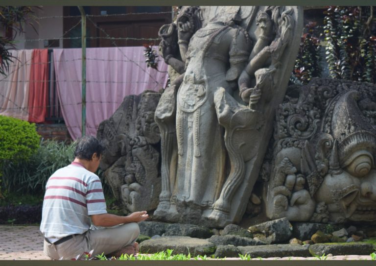 Close-up tangan membawa dupa saat berdoa di Candi Jago