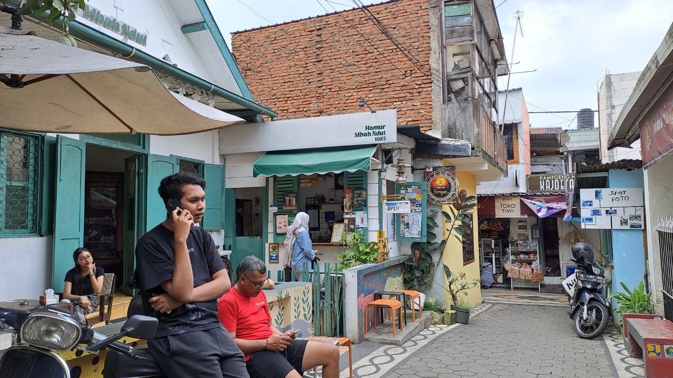 Pemuda sedang menelepon di depan kafe kawasan Kayutangan Heritage sebagai ilustrasi layanan kontak perjalanan