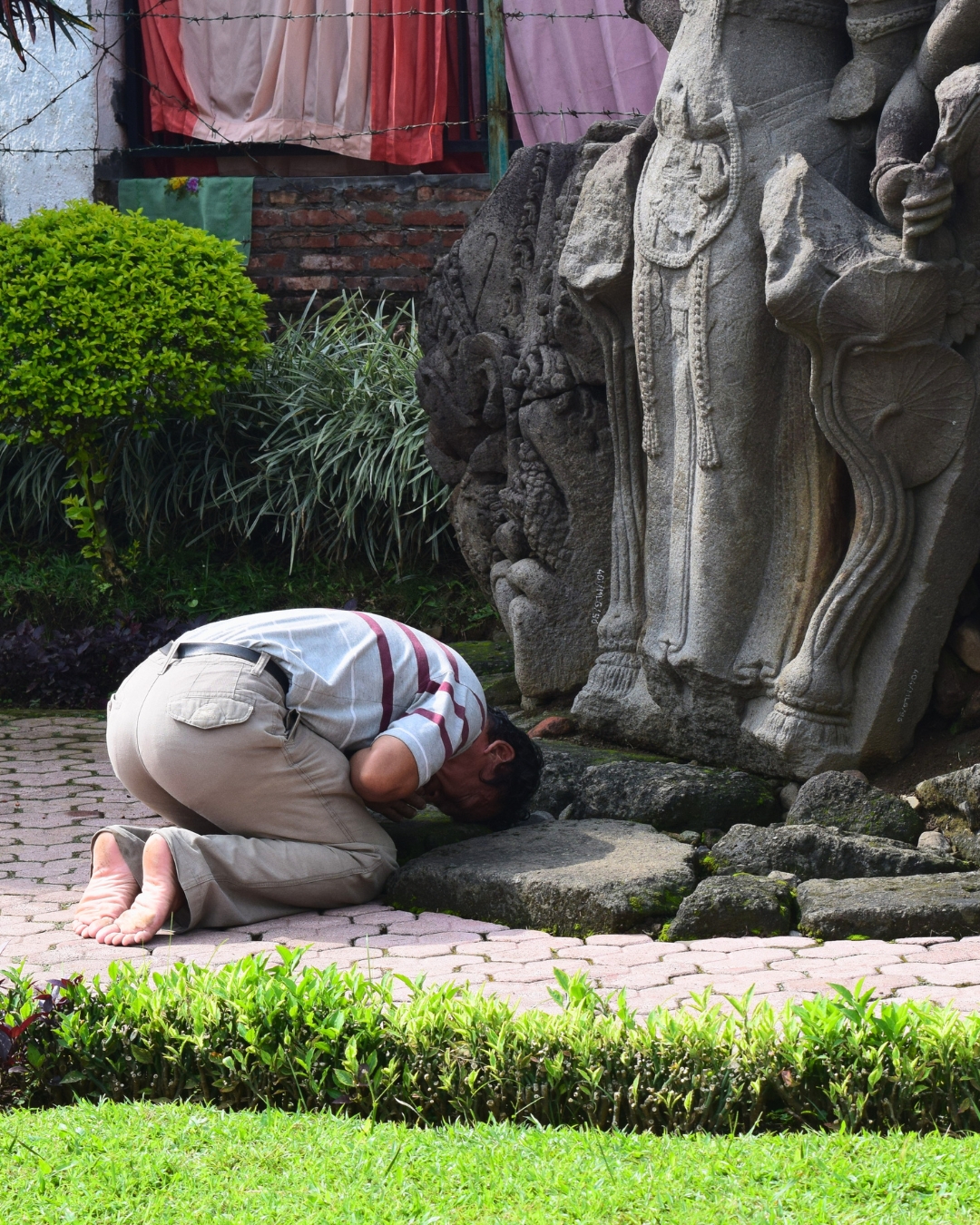 Ritual doa pengunjung di depan arca Candi Jago Malang dengan latar batu candi kuno