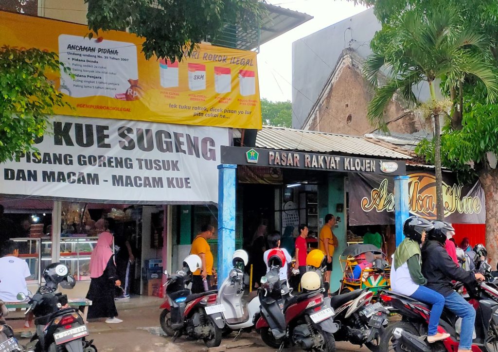 Tampak depan Pasar Rakyat Klojen Malang dengan aktivitas pengunjung dan kendaraan di area pasar